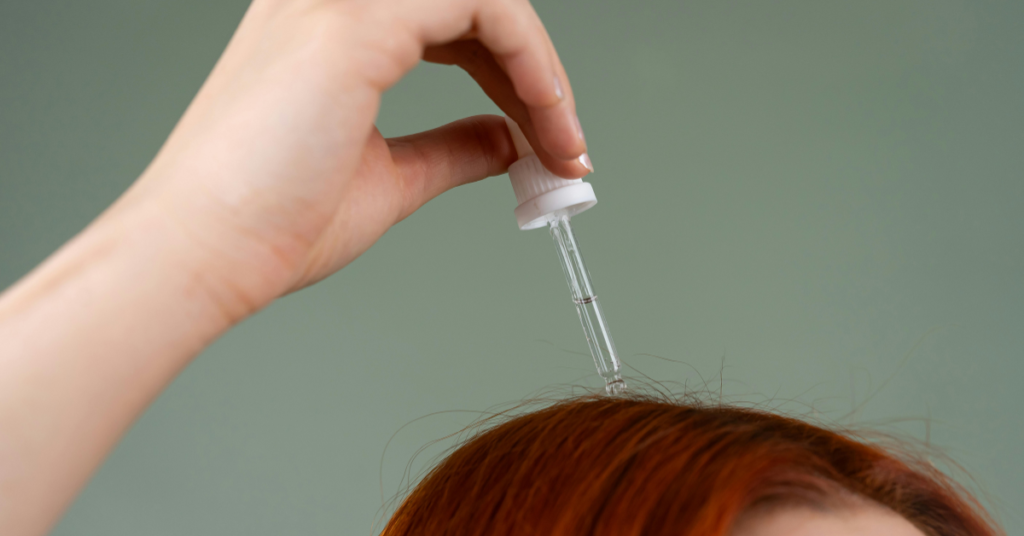 A woman applying rosemary oil to the scalp for hair growth